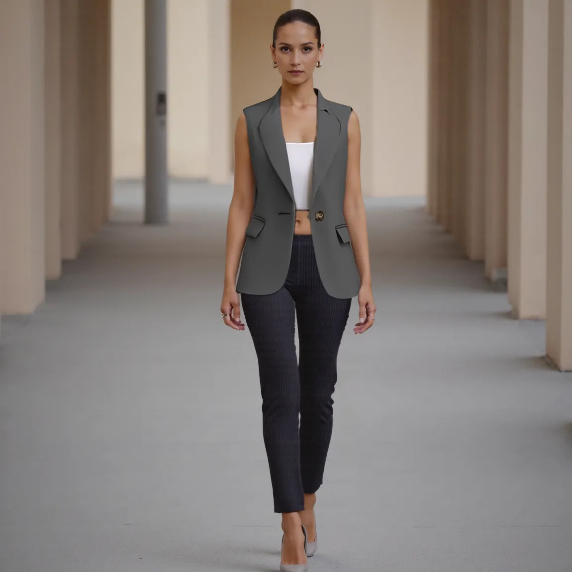 Woman wearing a gray vest and black pants in a architectural setting