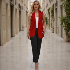 Woman in a red blazer and black pants walking down a sunlit street.