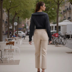 Woman walking on a city street wearing a black sweater and beige pants.