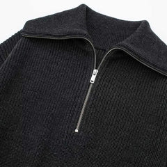 Close-up of a black ribbed knit sweater with a quarter zip on a white background
