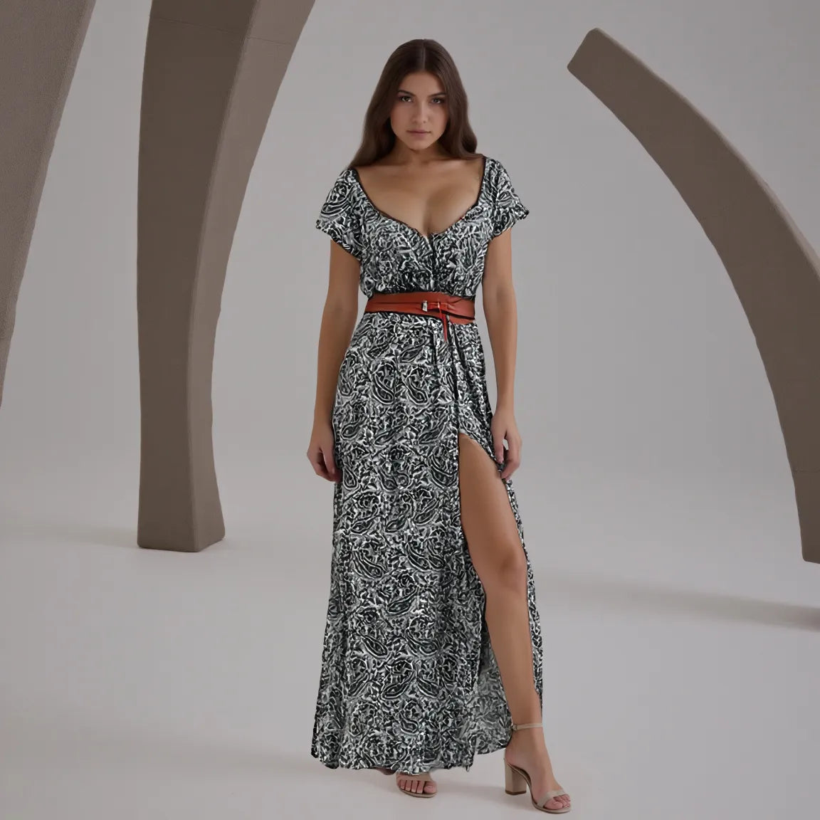 Woman wearing a black and white patterned dress with a brown belt against a neutral background