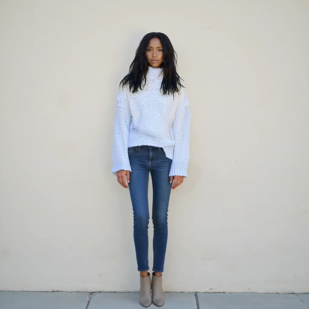 Person wearing a light blue sweater and dark blue jeans against a plain background