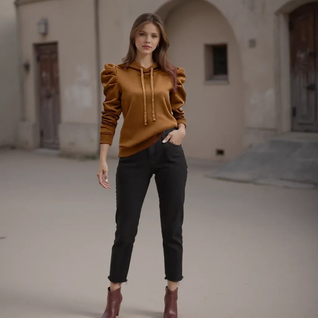 Woman wearing a mustard yellow hoodie and black pants standing in an urban setting.