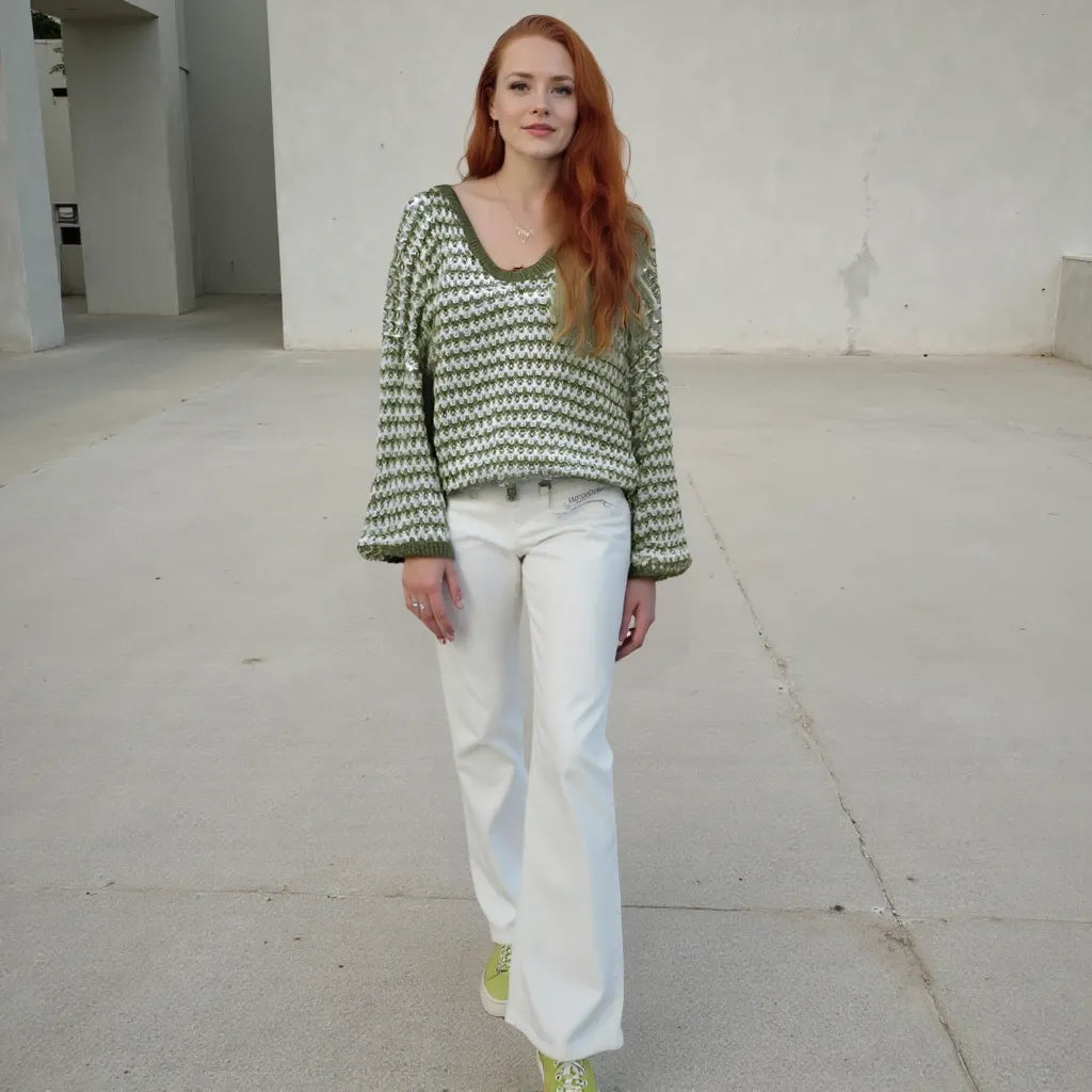 Woman wearing a green and white patterned sweater and white pants in an urban setting.