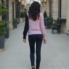 Woman walking down a city street with buildings and plants on either side.