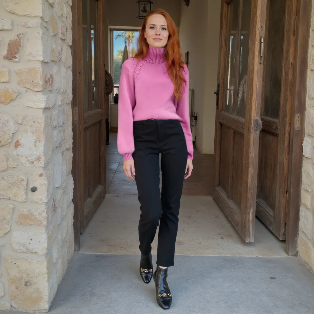 Woman in a pink sweater and black pants standing in a doorway.