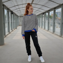 Woman wearing a striped sweater and black pants standing in an outdoor covered area.