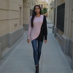 Woman walking down a city street wearing a pink sweater and black cardigan.