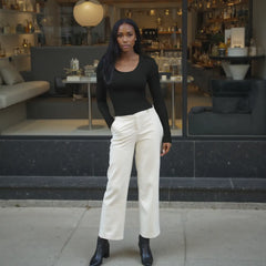 Woman in black top and white pants standing in a modern indoor setting