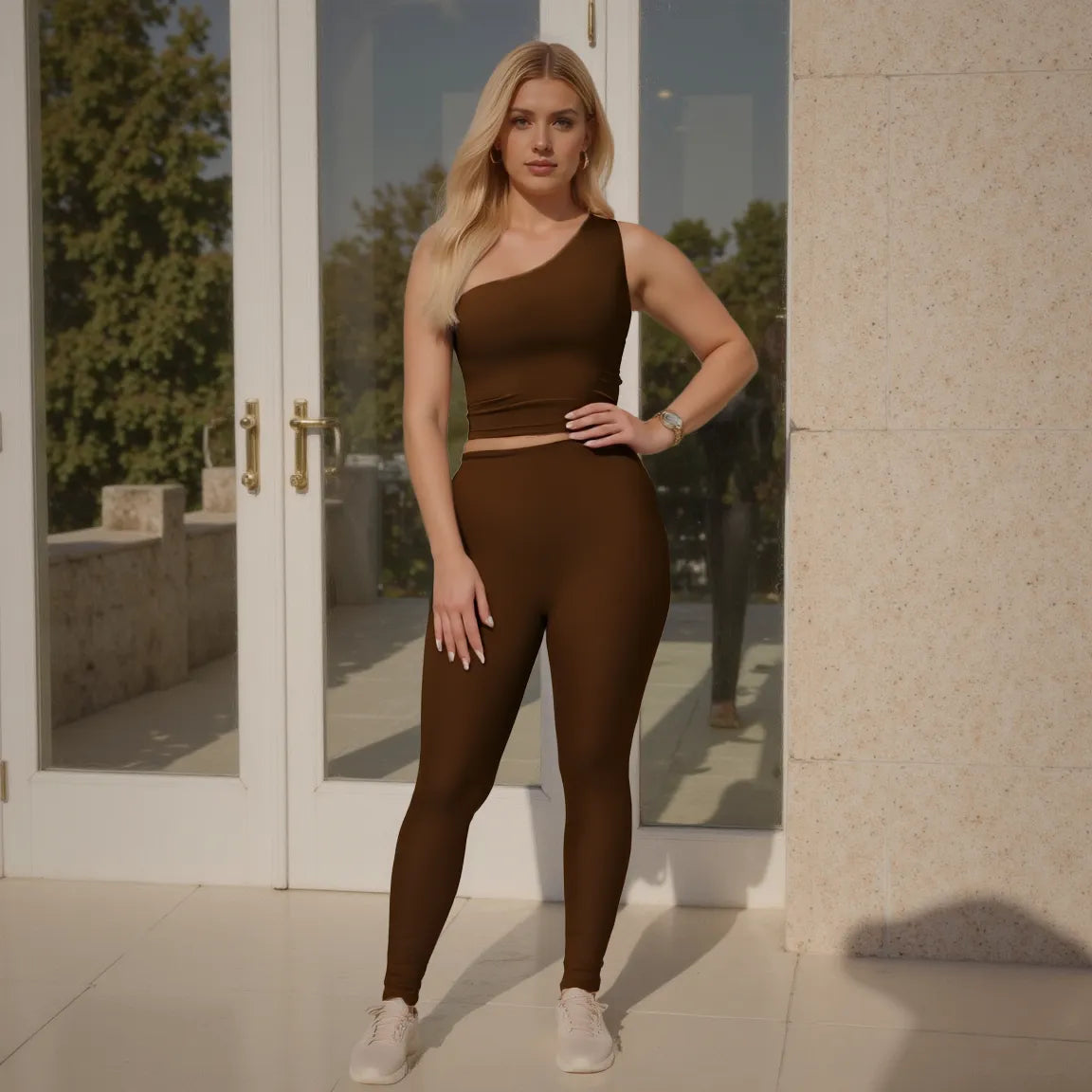 Woman in a brown athletic outfit standing in front of a glass door.