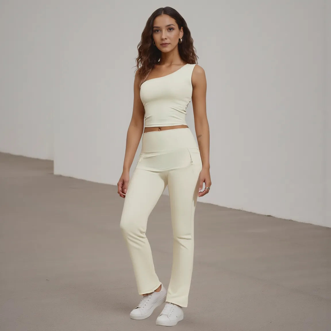 Woman wearing a light-colored outfit standing against a plain background